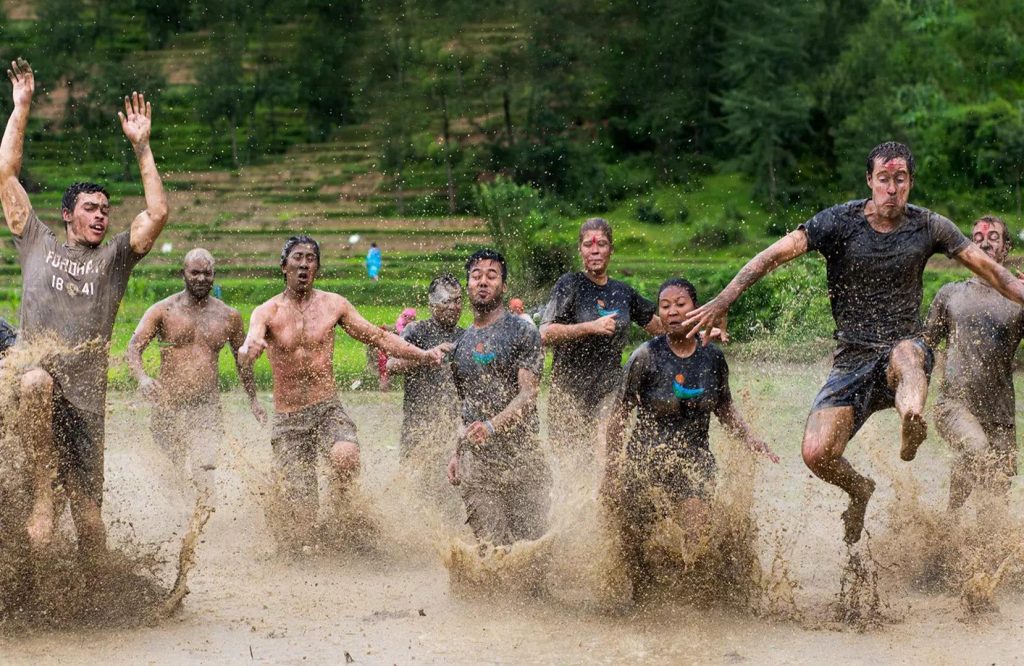 Farmers and visitors celebrating the Ropain Festival by planting rice seedlings and dancing in the mud during the rice planting season.