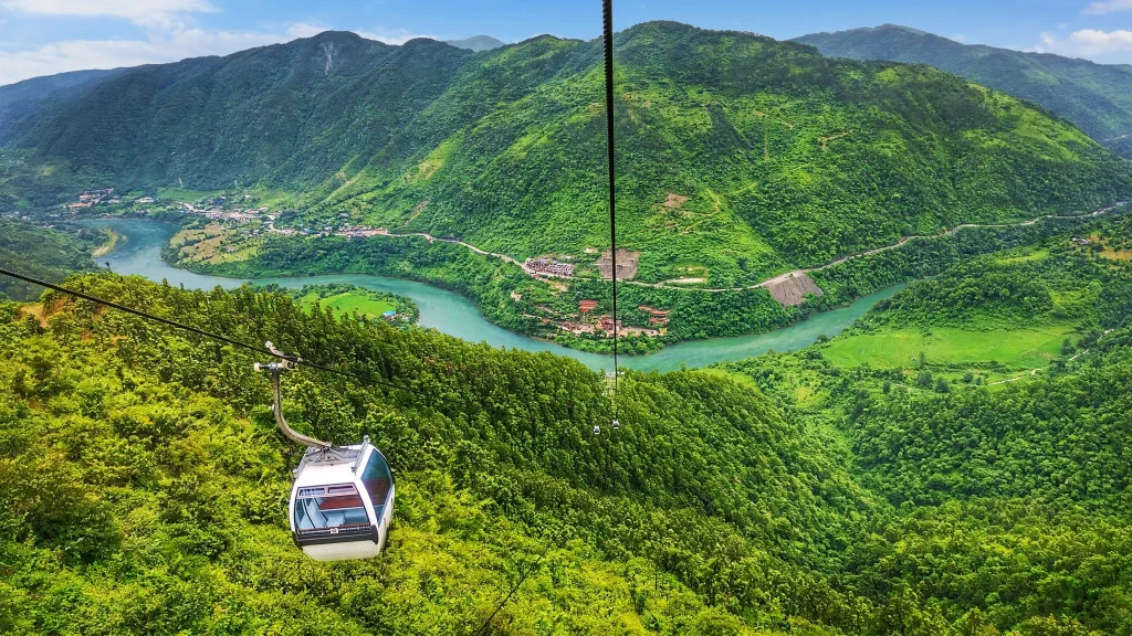 Aerial view of the Trishuli River winding through green hills with the Manakamana cable car overhead