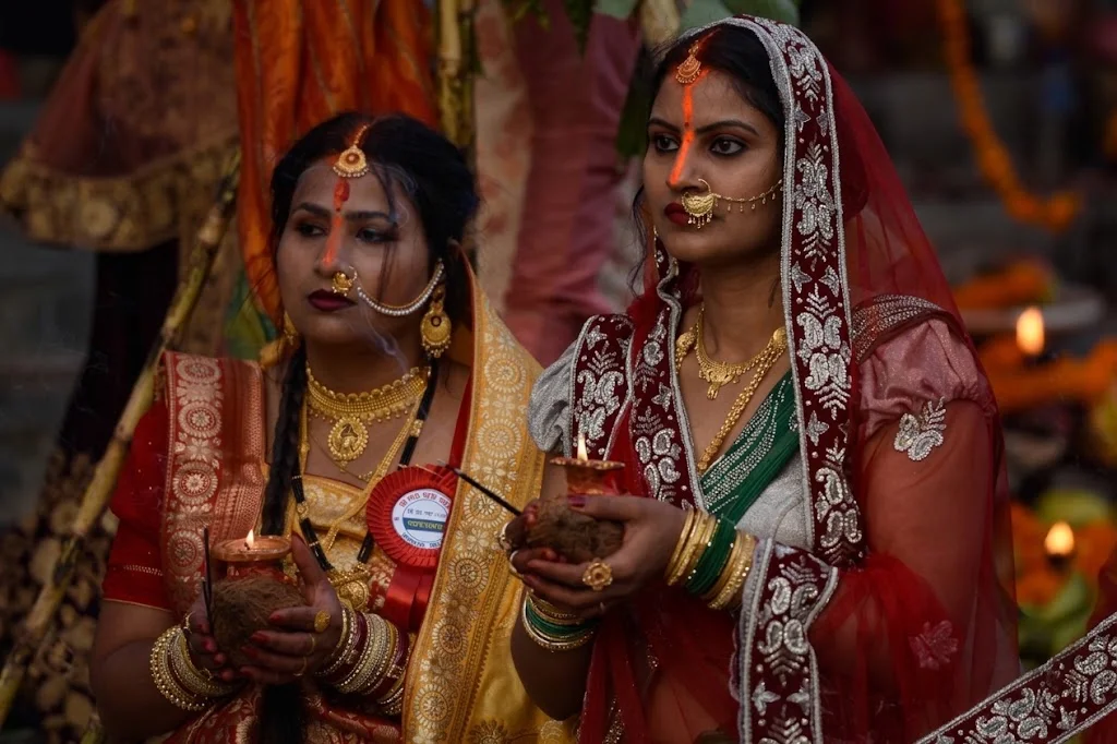 Married women wearing traditional attire holding oil lamps during Chhath festival reflecting Madhesi Identity in Nepal.