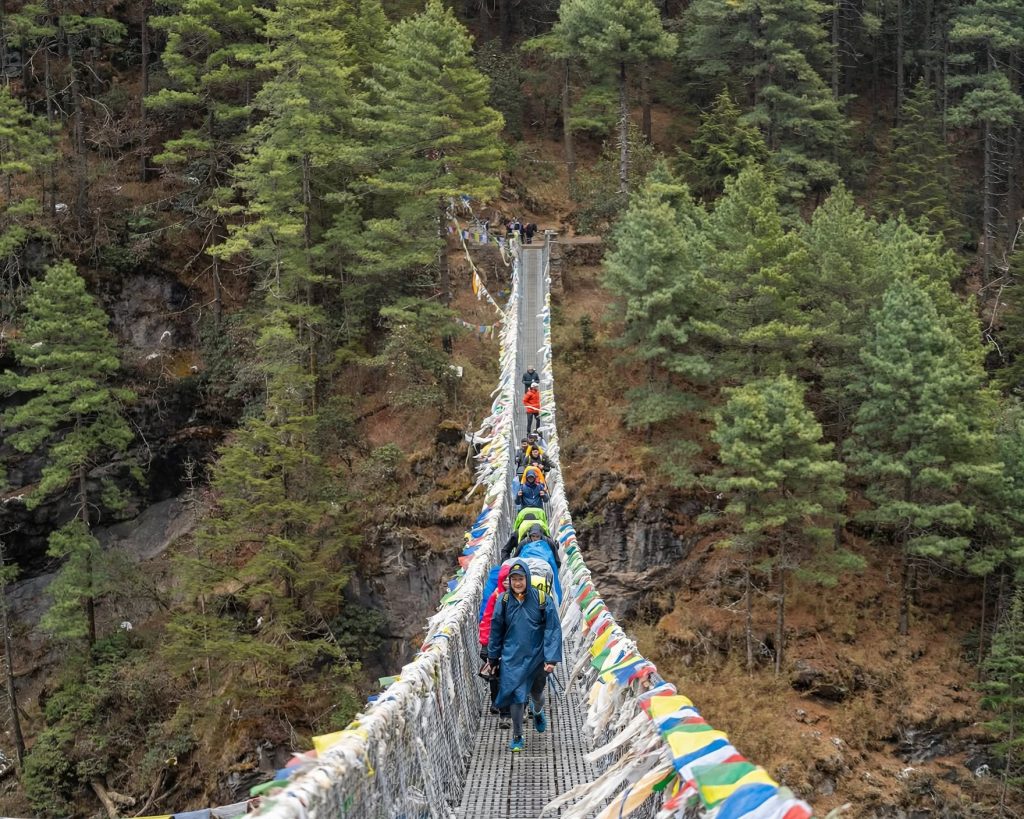 Trekkers queuing on a narrow suspension bridge during peak autumn season in the Khumbu region